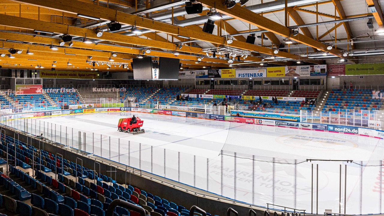 Eine Eisbearbeitungsmaschine faehrt vor leeren Raengen über die Eisflaeche in der Eisarena Bremerhaven.