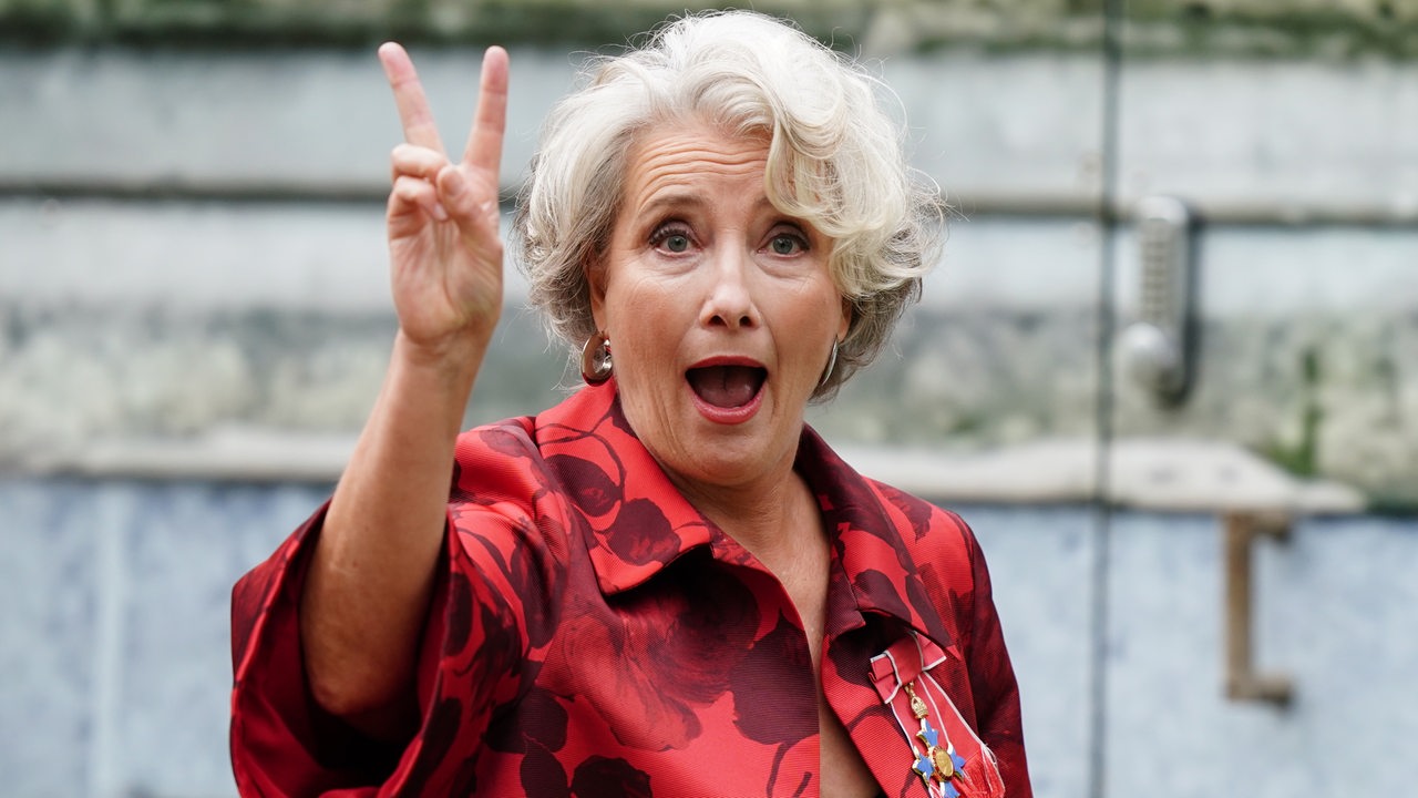 Emma Thompson hebt die Hand zum Victory Zeichen.